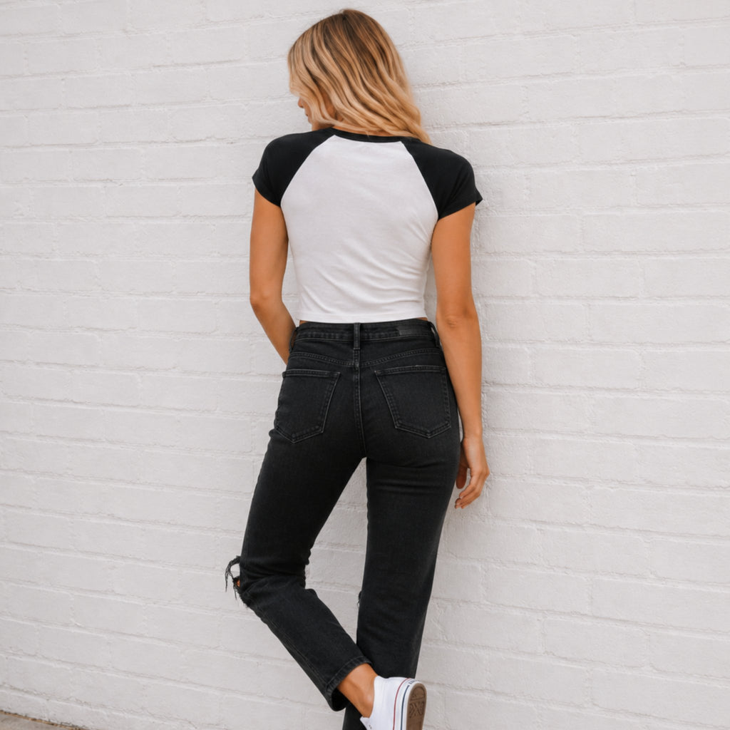 white and black raglan baby baseball t-shirt with a large red lipstick kiss and baseball stitching print on the front, paired with blue jeans.