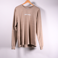 A vintage tan crewneck shirt hanging on a wooden hanger against a light  background, featuring the text 'HAPPILY BERSERK' printed in VINTAGE white on the chest.