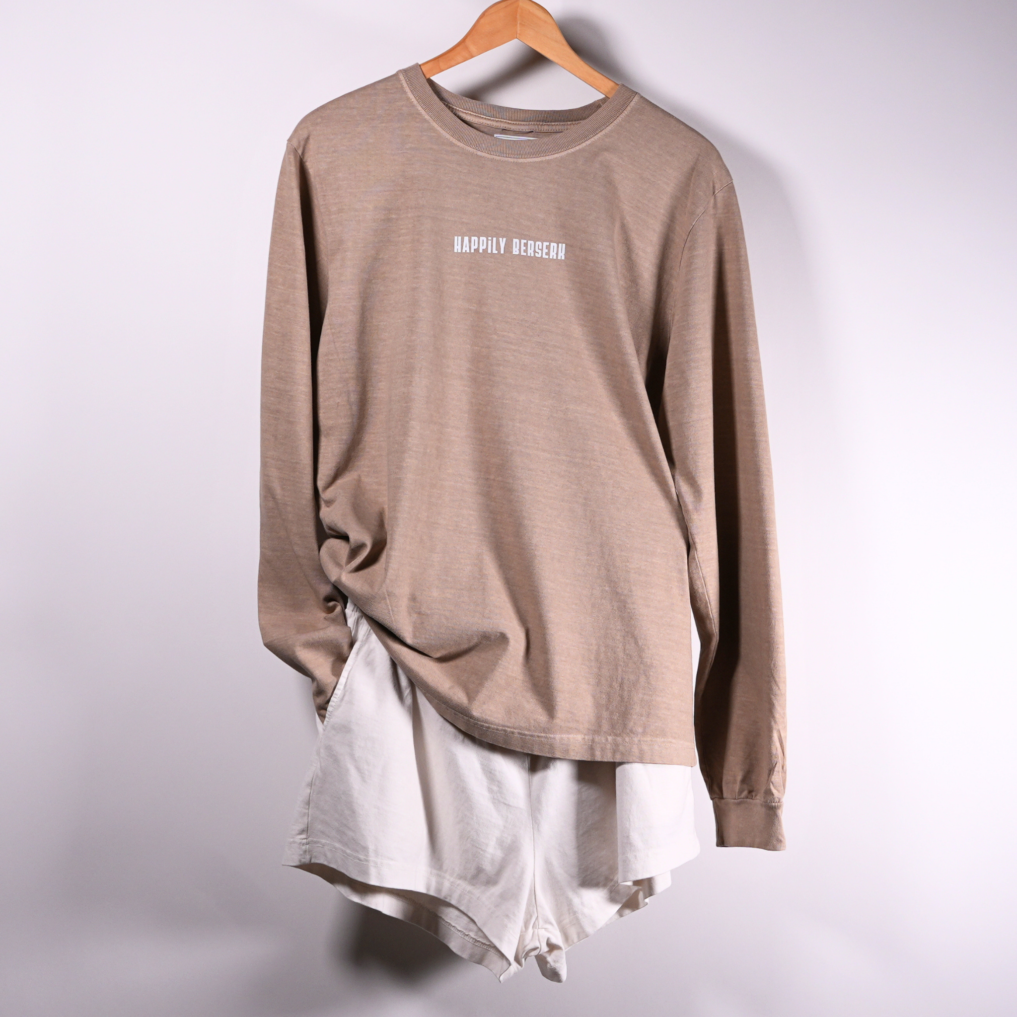 A VINTAGE TAN long-sleeve t-shirt with 'HAPPILY BERSERK' printed in white on the chest, layered over VINTAGE WHITE  HAPPILY BERSERK SHORTS 