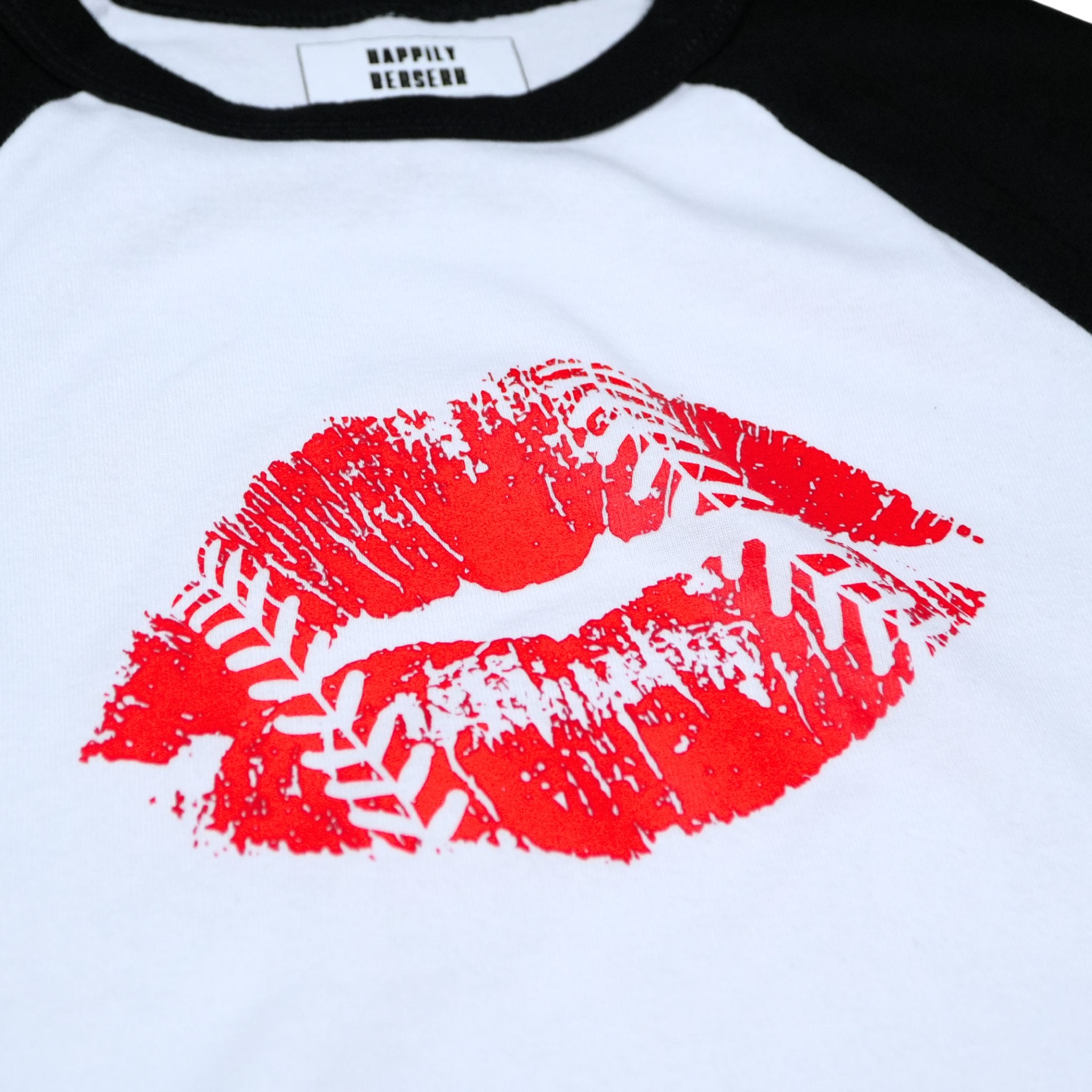 white and black raglan baby baseball t-shirt with a large red lipstick kiss and baseball stitching print on the front, paired with blue jeans.