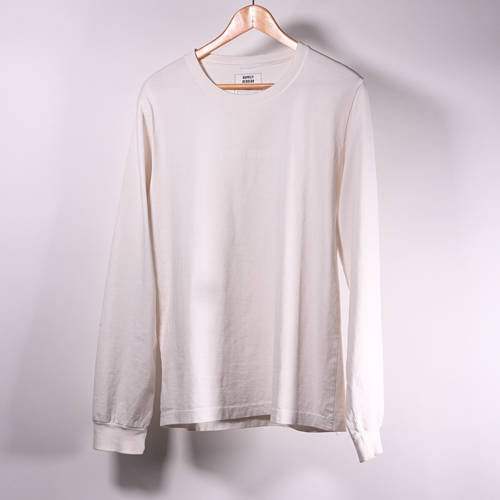 A long-sleeve happily berserk crewneck t-shirt in vintage white, hanging on a wooden hanger against a plain light  wall.